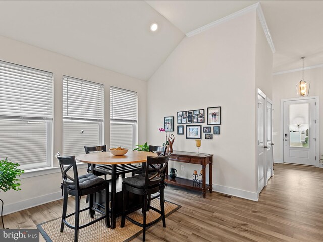 dining area featuring ornamental molding, baseboards, lofted ceiling, and light wood finished floors