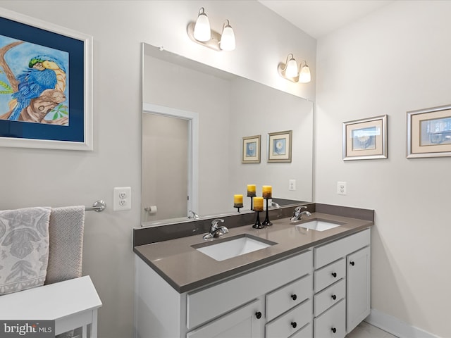 full bathroom featuring baseboards, double vanity, and a sink