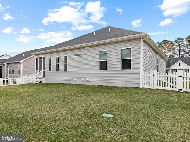 rear view of house featuring a lawn, a gate, entry steps, and fence