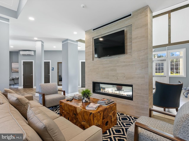 living area with a wall mounted air conditioner, a fireplace, baseboards, and recessed lighting