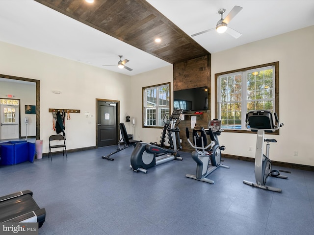 exercise room with baseboards, wooden ceiling, and a ceiling fan