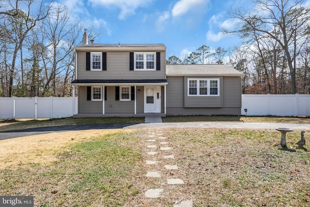 traditional home featuring a gate, a front yard, and fence