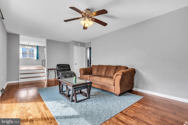 living area featuring stairway, baseboards, ceiling fan, and wood finished floors