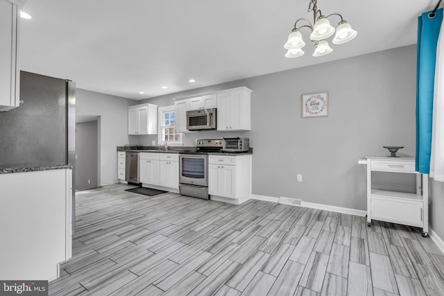 kitchen with a chandelier, stainless steel appliances, baseboards, visible vents, and white cabinets