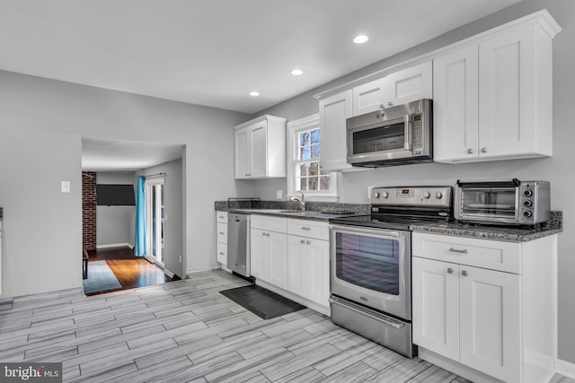 kitchen featuring white cabinets, wood tiled floor, stainless steel appliances, and a toaster