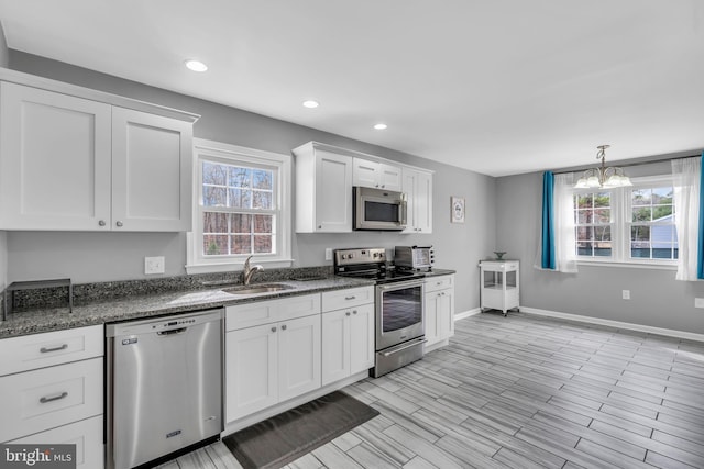 kitchen featuring white cabinets, a sink, stainless steel appliances, and a wealth of natural light