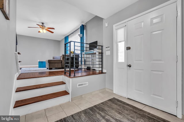 tiled foyer entrance with baseboards, stairs, ceiling fan, and visible vents
