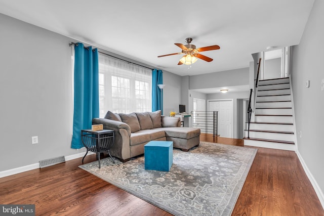 living room with a ceiling fan, wood finished floors, baseboards, and visible vents