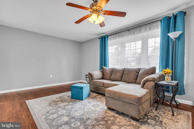 living area with a ceiling fan, baseboards, and wood finished floors