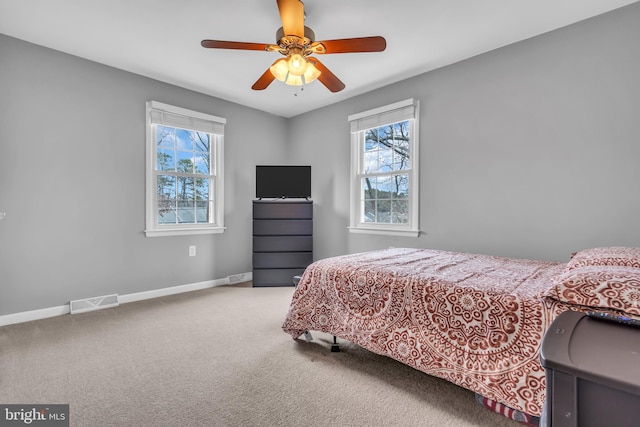 carpeted bedroom with multiple windows, visible vents, baseboards, and a ceiling fan