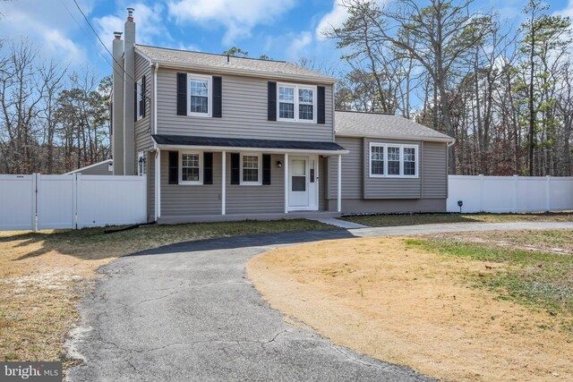 view of front facade with driveway, a chimney, fence, and a gate