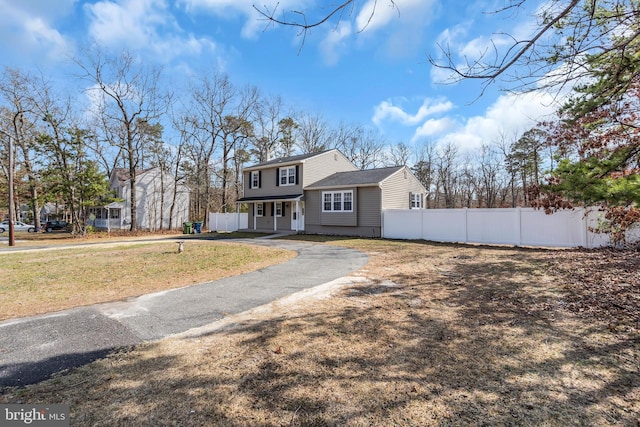 colonial-style house featuring driveway and fence
