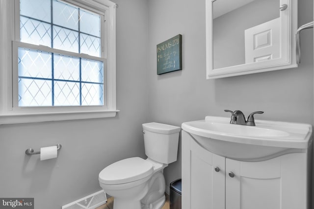 bathroom featuring toilet, vanity, and visible vents