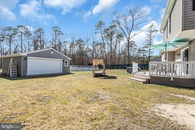 view of yard with an outbuilding, a detached garage, fence, and a deck