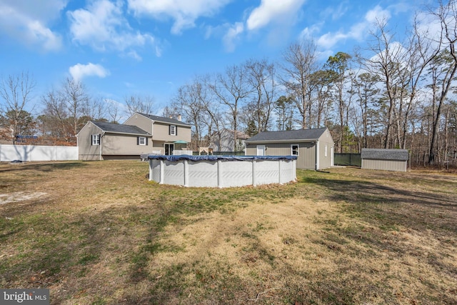 view of yard featuring a shed, an outbuilding, fence, and a covered pool