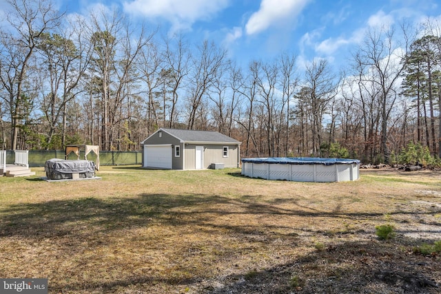 view of yard with fence, an outdoor structure, a garage, and a covered pool