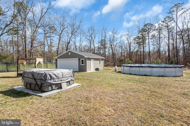 view of yard with an outbuilding, a detached garage, a covered pool, and fence