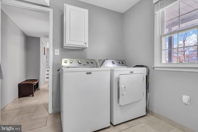 washroom featuring baseboards, cabinet space, independent washer and dryer, and light tile patterned floors