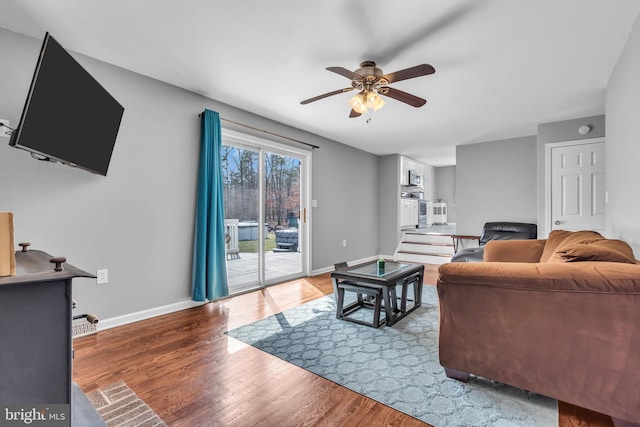 living area featuring baseboards, wood finished floors, and a ceiling fan
