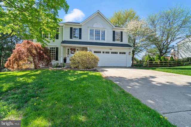 traditional-style house featuring an attached garage, a front yard, fence, and driveway
