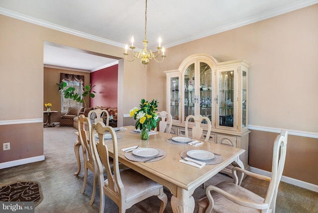 carpeted dining area featuring a chandelier, baseboards, and ornamental molding