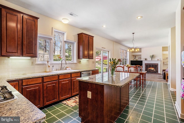 kitchen featuring visible vents, a center island, a sink, stainless steel appliances, and backsplash
