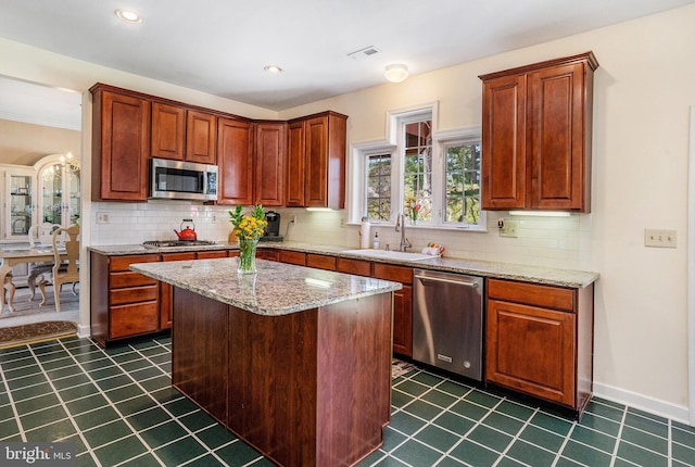 kitchen with backsplash, light stone countertops, visible vents, stainless steel appliances, and a sink
