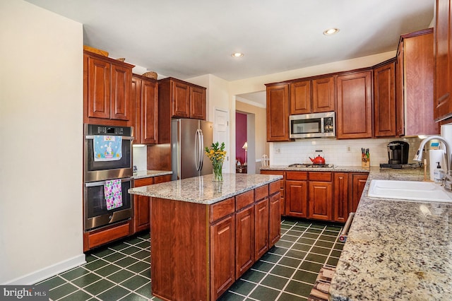 kitchen with tasteful backsplash, a center island, baseboards, a sink, and appliances with stainless steel finishes