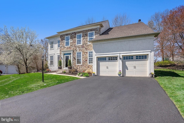 colonial house with a garage, stucco siding, a front yard, stone siding, and driveway