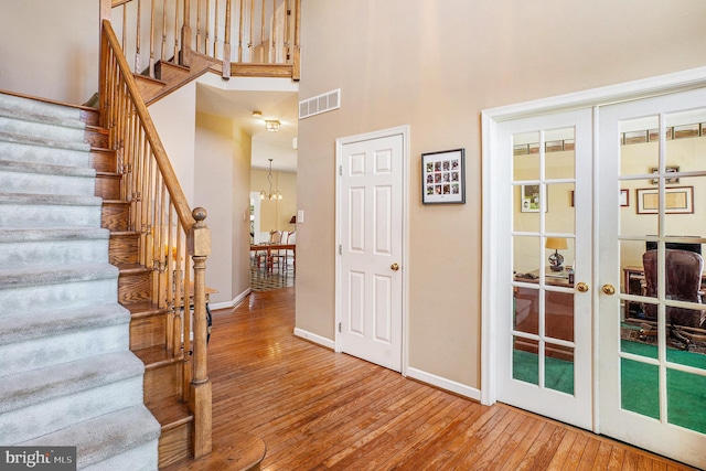 entrance foyer featuring wood-type flooring, visible vents, baseboards, and a high ceiling