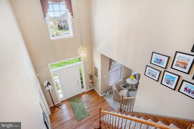 entrance foyer with a high ceiling, wood finished floors, baseboards, and an inviting chandelier