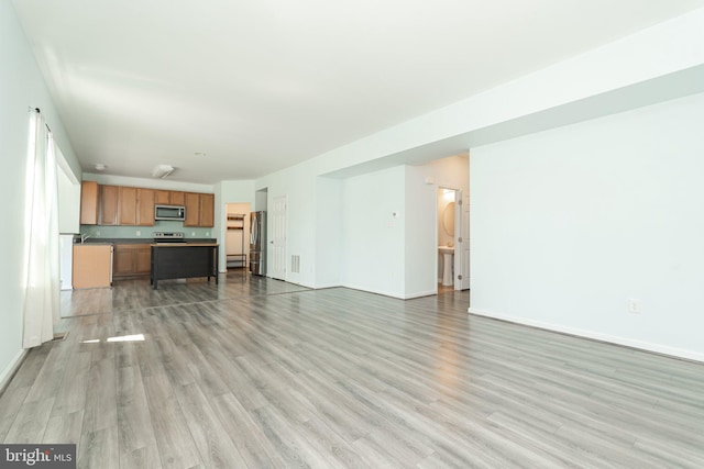 unfurnished living room featuring light wood finished floors and baseboards