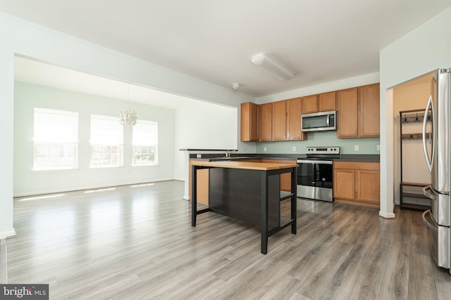 kitchen featuring stainless steel appliances, wood finished floors, a sink, and brown cabinetry