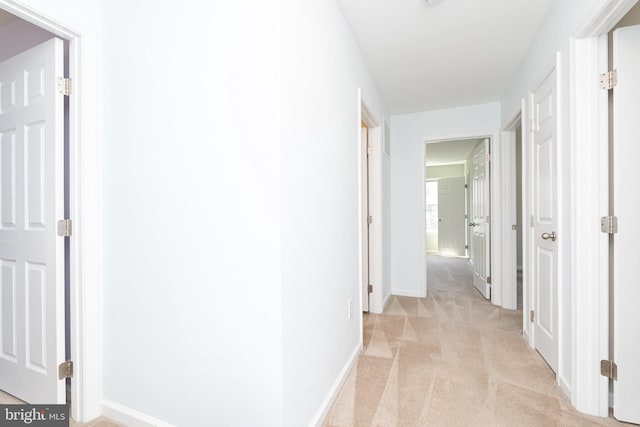 hallway with baseboards and light carpet