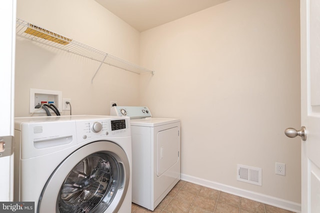 washroom featuring light tile patterned flooring, baseboards, visible vents, separate washer and dryer, and laundry area