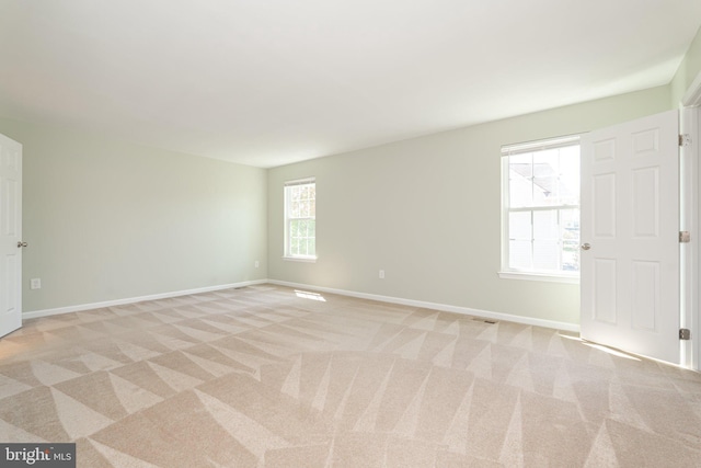 spare room featuring baseboards and light colored carpet