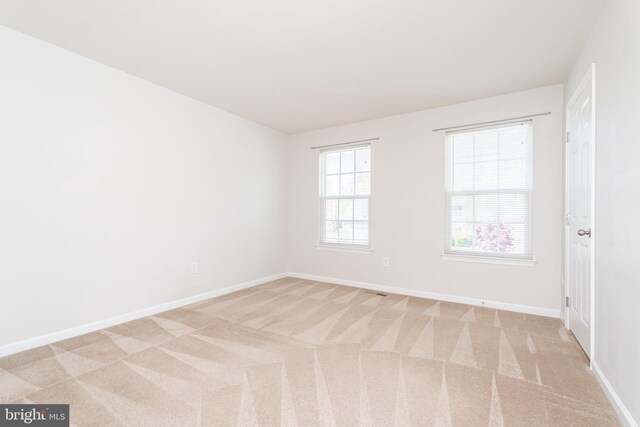 spare room with light colored carpet and baseboards