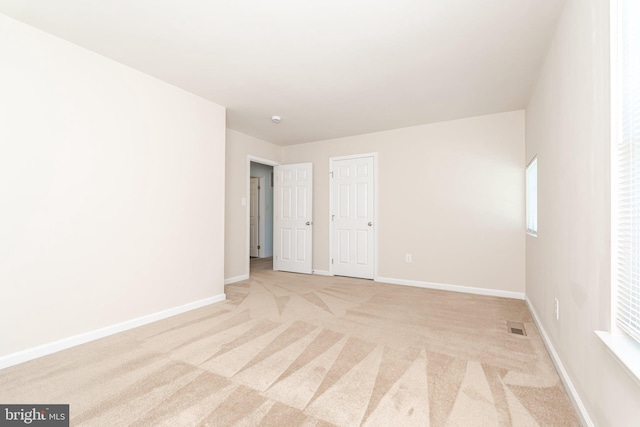unfurnished bedroom with baseboards, visible vents, and light colored carpet