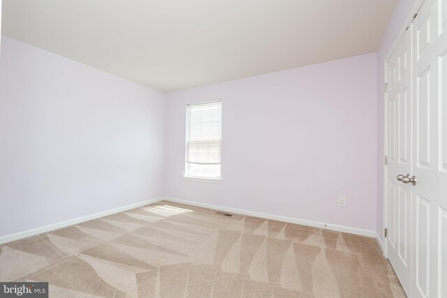 spare room with visible vents, light carpet, and baseboards