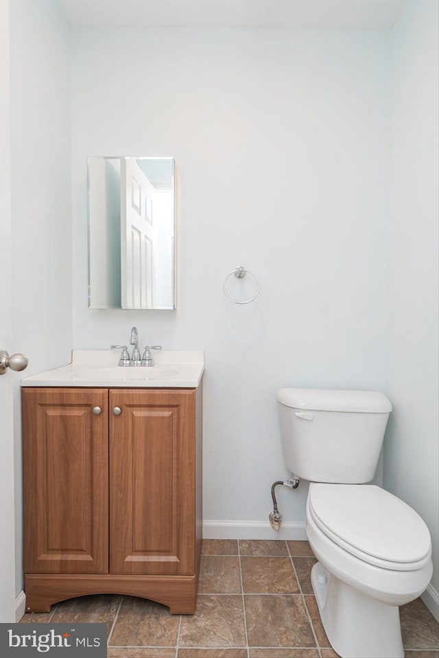 bathroom with baseboards, toilet, and vanity