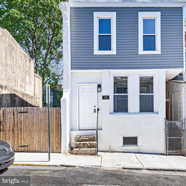 traditional home with fence, stucco siding, and entry steps