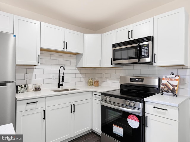 kitchen with a sink, backsplash, stainless steel appliances, and white cabinetry
