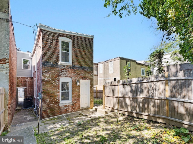 back of property featuring brick siding, central AC unit, and a fenced backyard