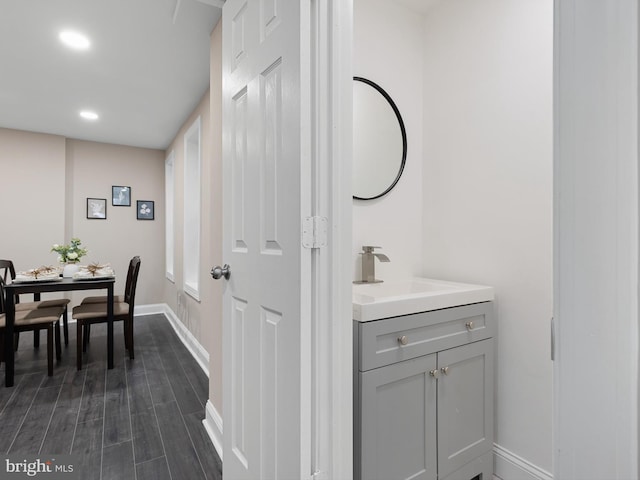 bathroom featuring baseboards, vanity, recessed lighting, and wood finished floors