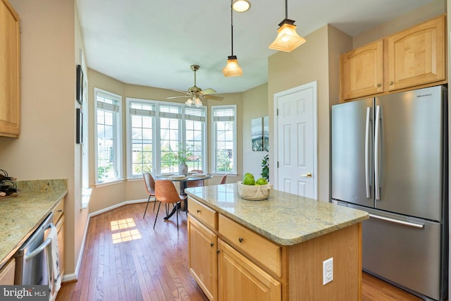 kitchen featuring appliances with stainless steel finishes, light brown cabinets, light wood-style flooring, a center island, and a ceiling fan