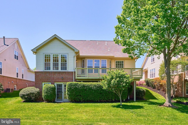 rear view of house with a lawn, a wooden deck, cooling unit, and brick siding