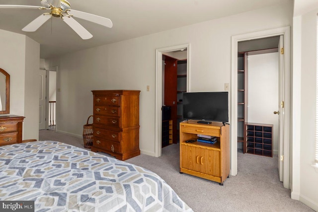 bedroom featuring light carpet, a walk in closet, and baseboards