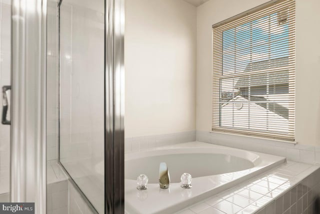 bathroom featuring a bath and a shower with door