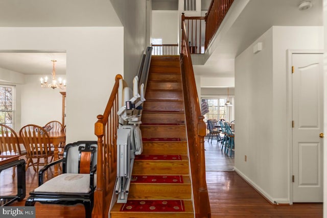 stairway featuring a notable chandelier, baseboards, and wood finished floors