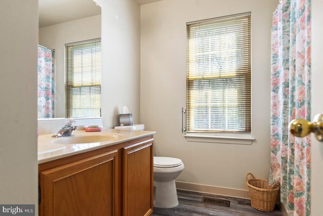 full bathroom featuring vanity, baseboards, toilet, visible vents, and wood finished floors